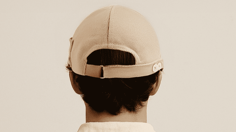 Person wearing a beige cap on a plain background