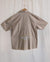 Brown shirt with yellow fox designs on a hanger against a beige background