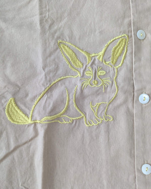 Embroidered canidae design on a light-coloured fabric with white buttons and yellow stitching.