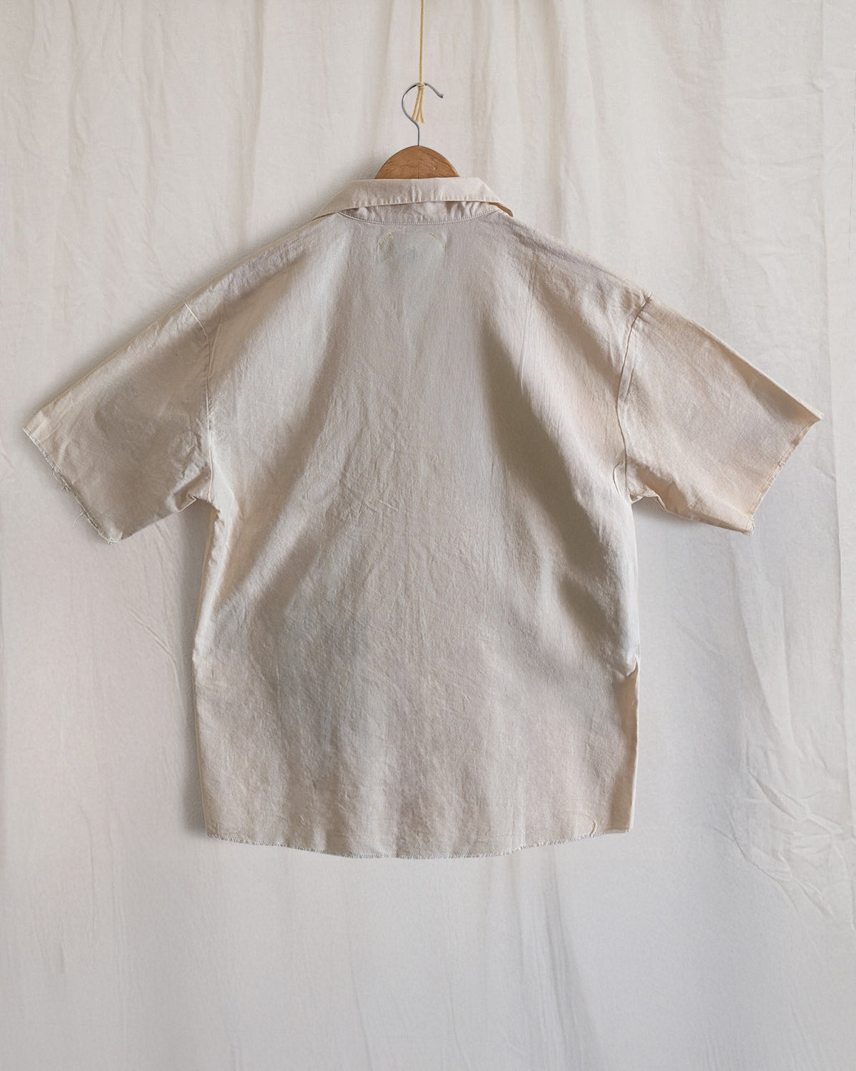 Beige back shirt on a hanger against a white background