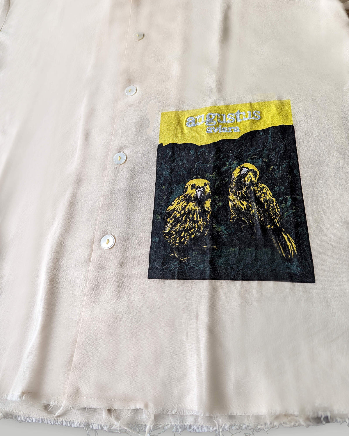 Close-up of a shirt with a pocket featuring a bird design and 'Augustus' branding.