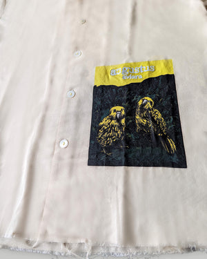 Close-up of a shirt with a pocket featuring a bird design and 'Augustus' branding.